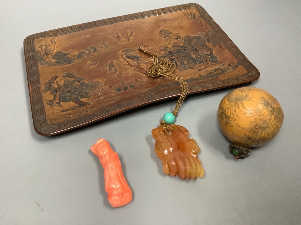 A Chinese carved hardstone pendant, a carved coral Guanyin, an engraved nut pendant, and a lacquered tray